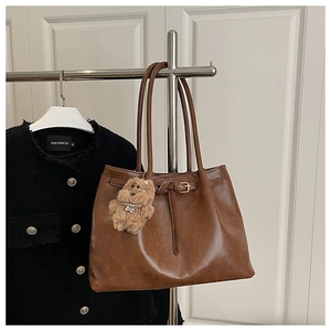 Detailed shot of brown vintage tote bag with gold buckle and plush bear charm