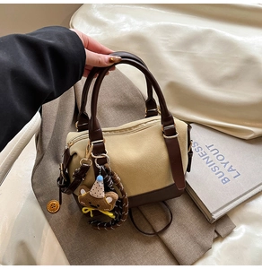 Détail du sac en daim kaki avec garniture en cuir marron et pendentif ours en peluche