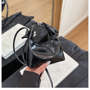 Detail of black glossy handbag featuring a unique circular cutout handle and white text
