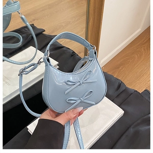 Gros plan sur le sac en cuir verni bleu clair avec des nœuds et des crochets métalliques