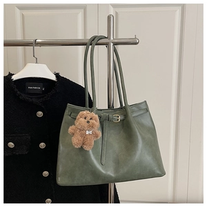 Close-up of olive green tote bag with textured faux leather and plush dog charm