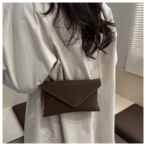 Detail of dark brown envelope crossbody bag with V-shaped woven texture and gold chain strap