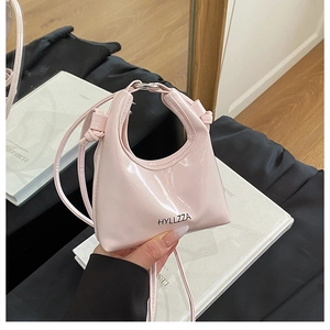Detailed macro view of a glossy pink patent leather mini handbag with top handle strap