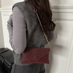 Sac bandoulière enveloppe bordeaux avec motif léopard porté par un mannequin femme
