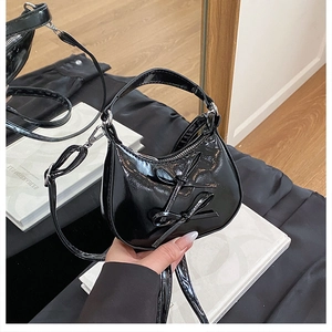 Détail du sac croissant en cuir verni noir avec nœuds 3D et fermeture éclair argentée