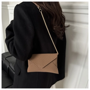 Close-up of brown textured leather crossbody bag with elegant gold chain strap detail