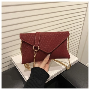Detail of burgundy envelope chain bag featuring a unique knitted texture and gold chain