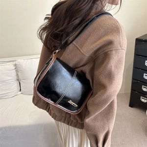 Sac bandoulière vintage noir et marron porté sur un manteau en laine camel