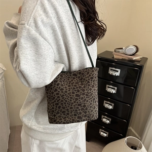Vintage leopard print bucket bag with green shoulder straps in a cozy indoor setting