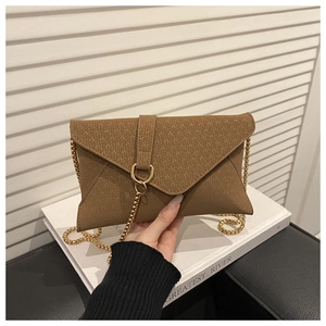 Close-up of brown textured envelope bag featuring gold chain strap and metal ring buckle