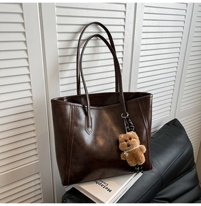 Detail of dark brown tote bag in retro faux leather with cute plush bear charm