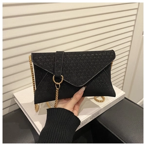 Detail of black woven envelope bag with gold ring closure and sleek snake chain strap
