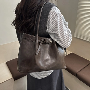 Minimalist vintage brown leather tote bag worn by a model in a sunlit indoor setting
