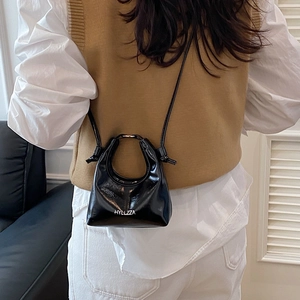 Chic black patent leather crossbody bag with circular handle and white logo lettering
