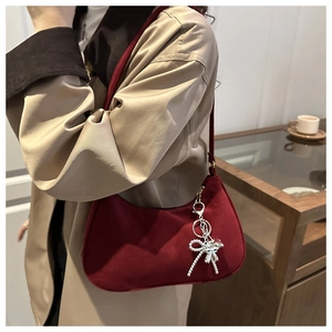 Macro shot of dark red velvet hobo bag with elegant silver bow pendant and strap