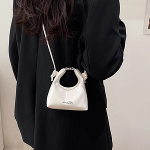 Mini white crossbody bag with top handle and black logo, worn with a black blazer