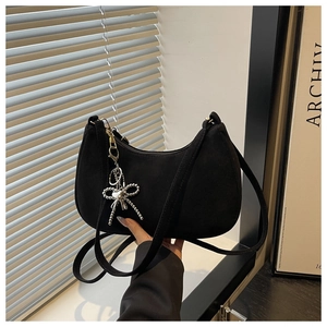 Detail of black suede hobo bag with silver beaded bow charm and heart element pendant