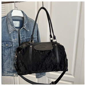 Detail of black pleated texture bag with golden hardware and embossed brand lettering