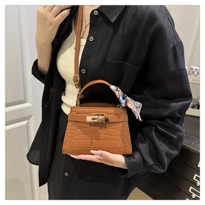 Detail of caramel crocodile pattern Kelly bag with silk scarf on handle and gold lock