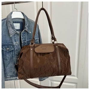 Close-up of deep brown tote bag with wrinkled texture fabric and gold hardware details