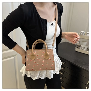 Détail d'un mini sac chic à imprimé cerise avec poignées en cuir et bandoulière