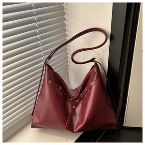 Detail of burgundy leather tote bag showing smooth texture and golden metal buckle