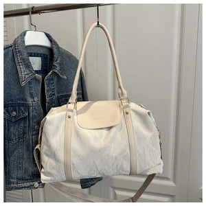 Detail of off-white wrinkled leather travel bag hanging on a hanger with denim jacket