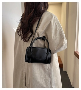 Rear view of a minimalist black leather square handbag with twin handles and fashion text