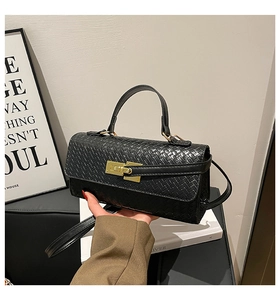 Détail du sac à main en cuir tressé noir avec fermoir doré et texture fine