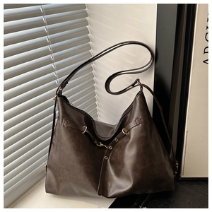 Detail of dark brown vintage PU leather hobo bag with metal eyelet strap on windowsill