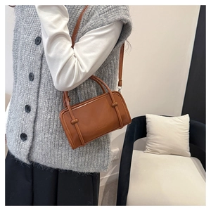 Side view of a brown box-style handbag with FASHION engraving worn by a model