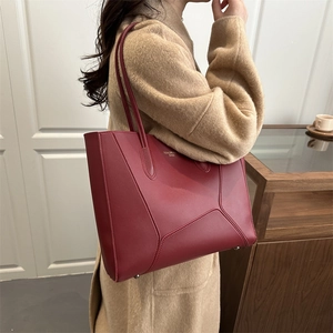 Chic burgundy leather tote bag with geometric stitching shown on a model in wool coat