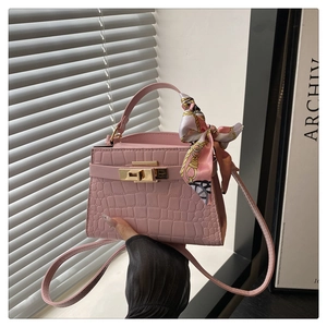 Detail of pink croc-embossed mini handbag with decorative scarf on the handle