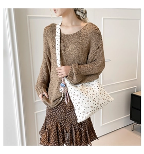Détail du sac à épaule en toile blanche avec imprimé cœurs et nœuds et breloque singe rose