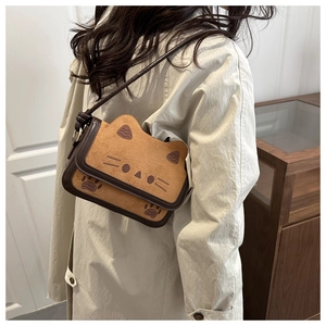 Detail of cute cat shaped brown suede shoulder bag with embroidered ears and paws