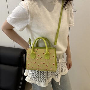 Mini sac rectangulaire vert clair à imprimé cerise porté par un mannequin