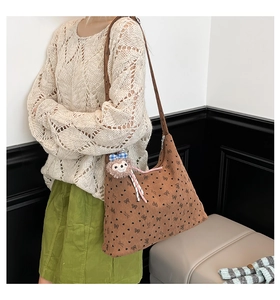 Détail d'un sac cabas en velours marron avec imprimés nœuds noirs et pendentif d'ours