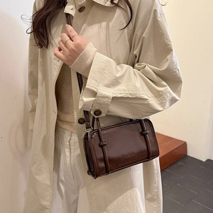 Brown rectangular crossbody bag with FASHION logo worn by a model in a beige trench coat