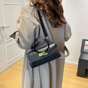 French style black woven Kelly bag with gold lock shown in a lifestyle model shot