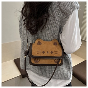 Detail of cute cat-shaped crossbody bag with embroidered whiskers and suede texture