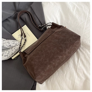 Detail of vintage brown tote bag with metal chain strap and textured leather finish