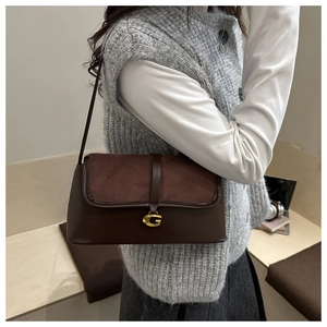 Close-up of a retro dark brown baguette bag with golden G-logo and suede patchwork