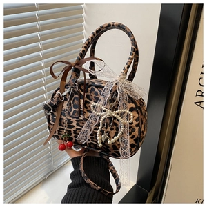 Detail of leopard print handbag with white lace bows and pearl cherry pendants