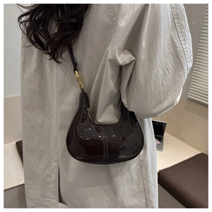 Detail of dark brown glossy patent leather hobo bag with sleek gold hardware accents