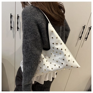 Détail d'un sac sous le bras blanc triangulaire orné de clous métalliques dorés