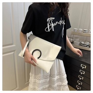 Detail of white envelope clutch bag with large black decorative buckle and wrist strap