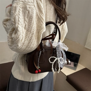 Brown bow crossbody pillow bag with cherry and lace details on a model in knitwear
