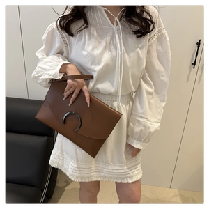 Brown leather envelope clutch bag with dark C-shaped metal clasp and thin handle