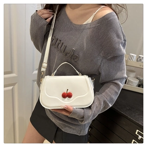 Close-up of white minimalist crossbody bag featuring red cherry ornaments and smooth PU leather
