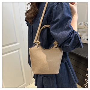Detail of khaki bucket bag featuring cartoon embossed textures and metallic ring handle